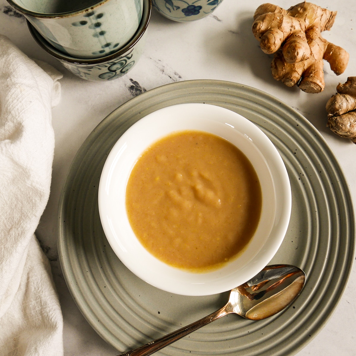 Homemade miso sauce in a small white cup resting on a gray plate.