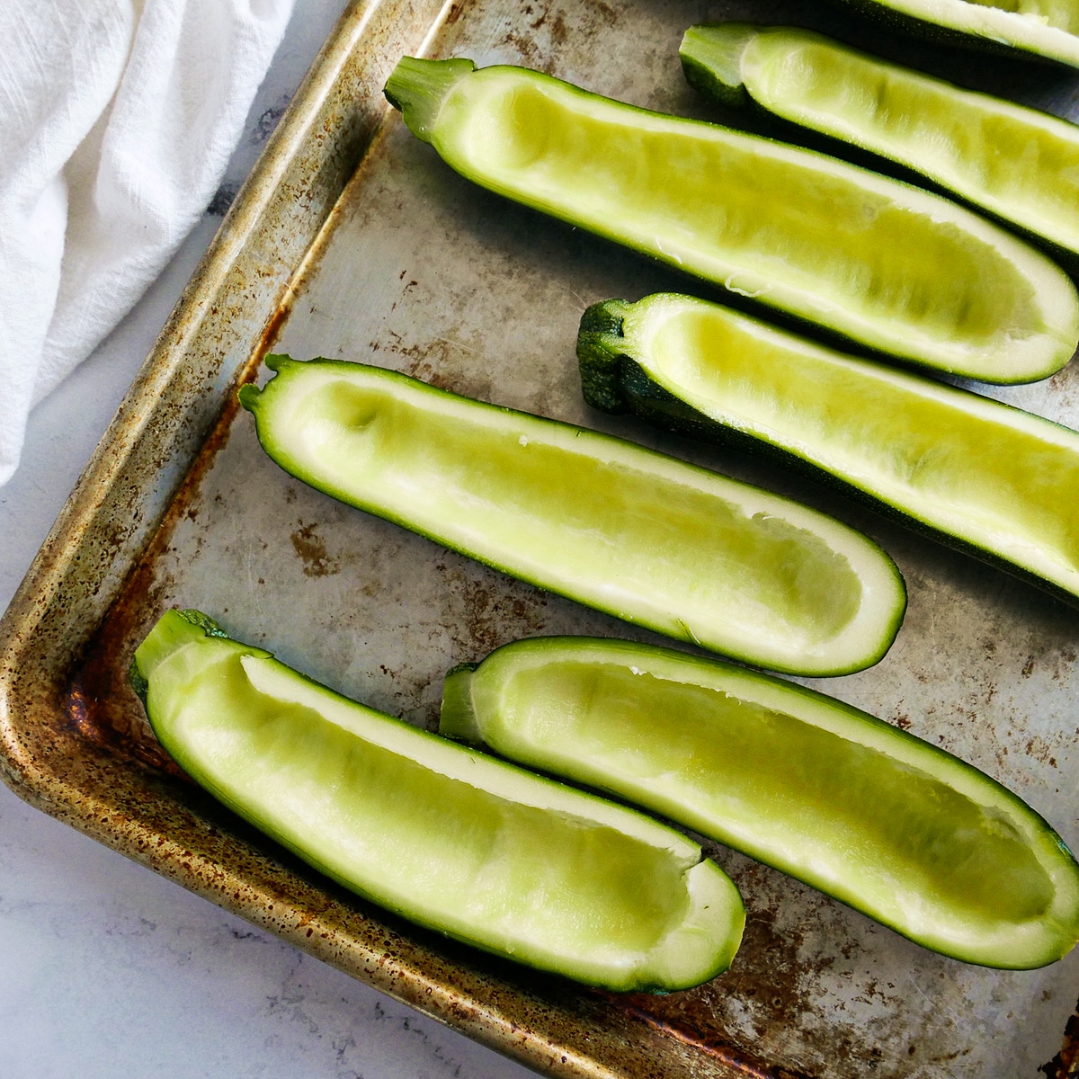 hollowed-out-zucchini.jpg Hollowed out zucchini halves placed on a baking sheet.