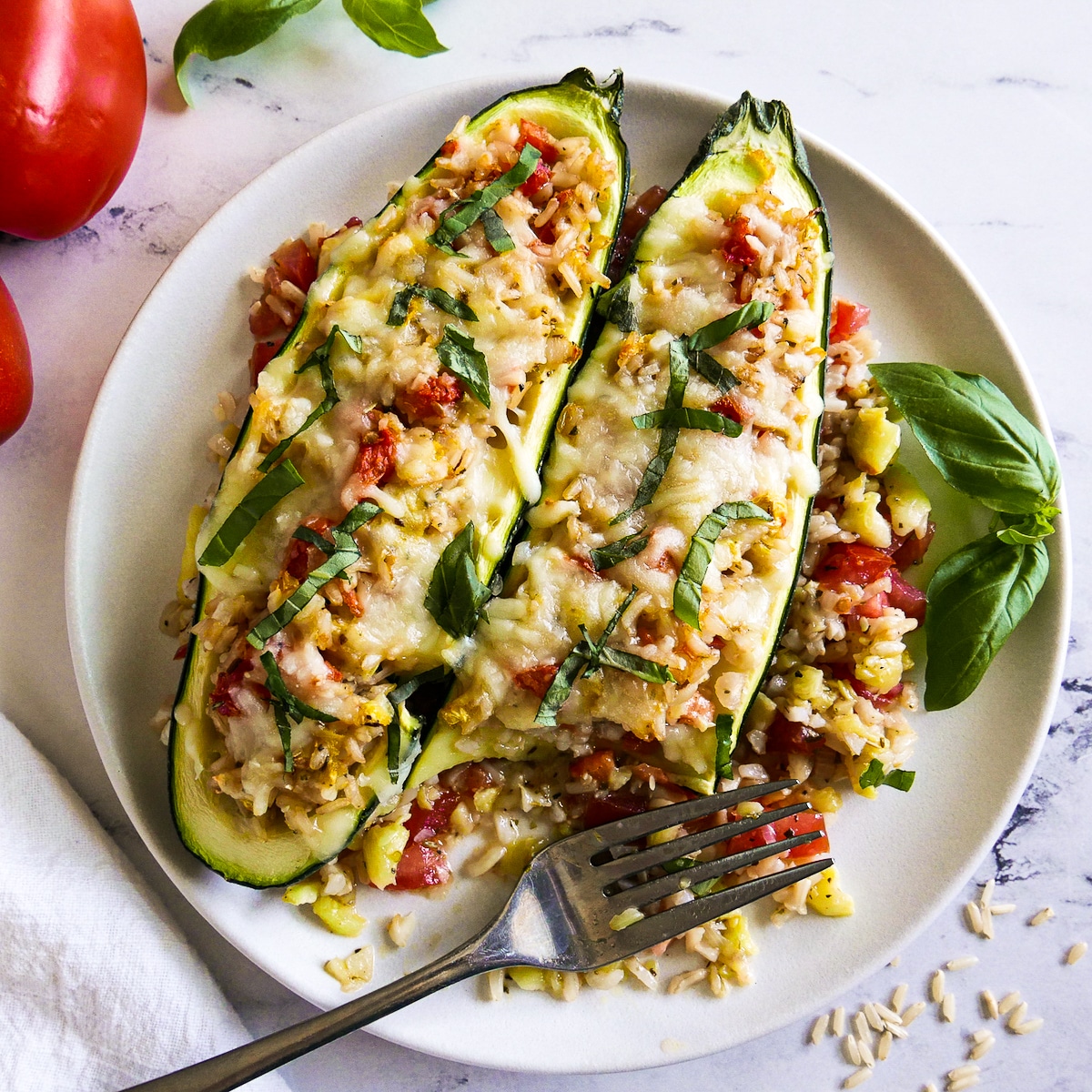 zucchini-boats-with-fork.jpg Two zucchini boats with a bite missing and fork resting on the plate.