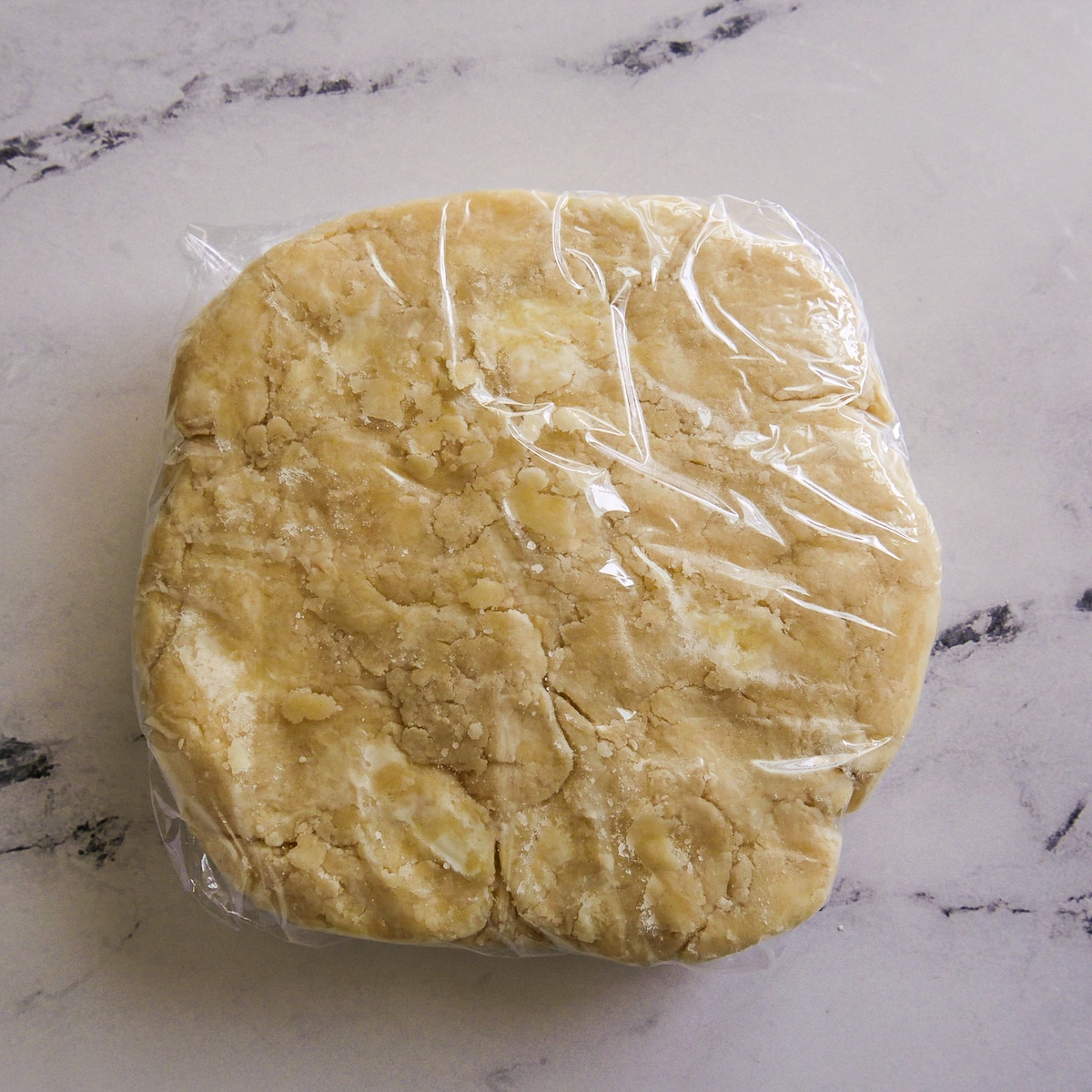 plastic-wrapped-dough.jpg Dough wrapped in plastic wrap and flattened into a disc.