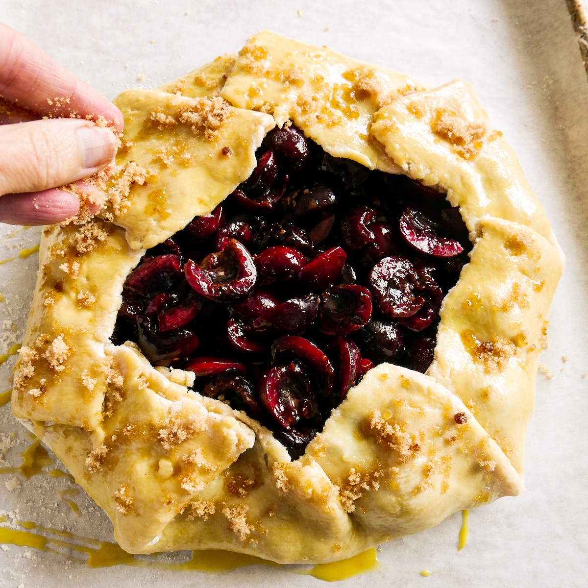 Sprinkling brown sugar onto top of assembled galette.