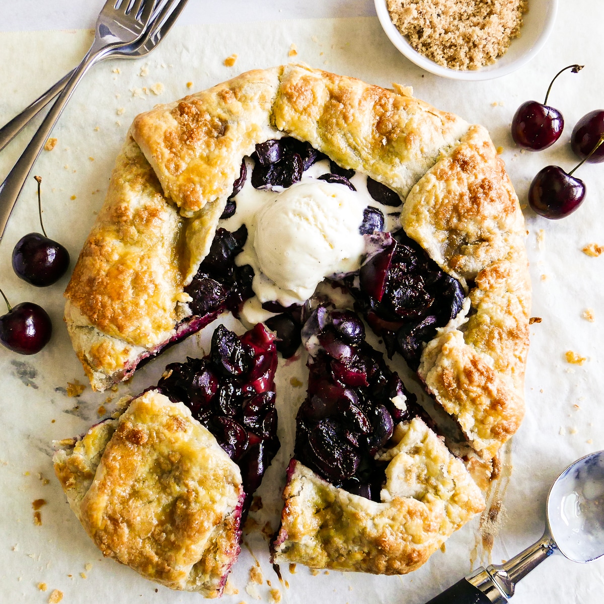 Rustic cherry galette topped with vanilla ice cream.