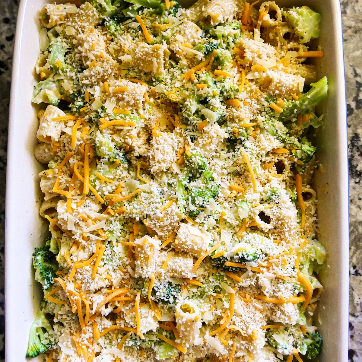 Cheese and breadcrumb topping sprinkled on top of prepared pasta in baking dish.