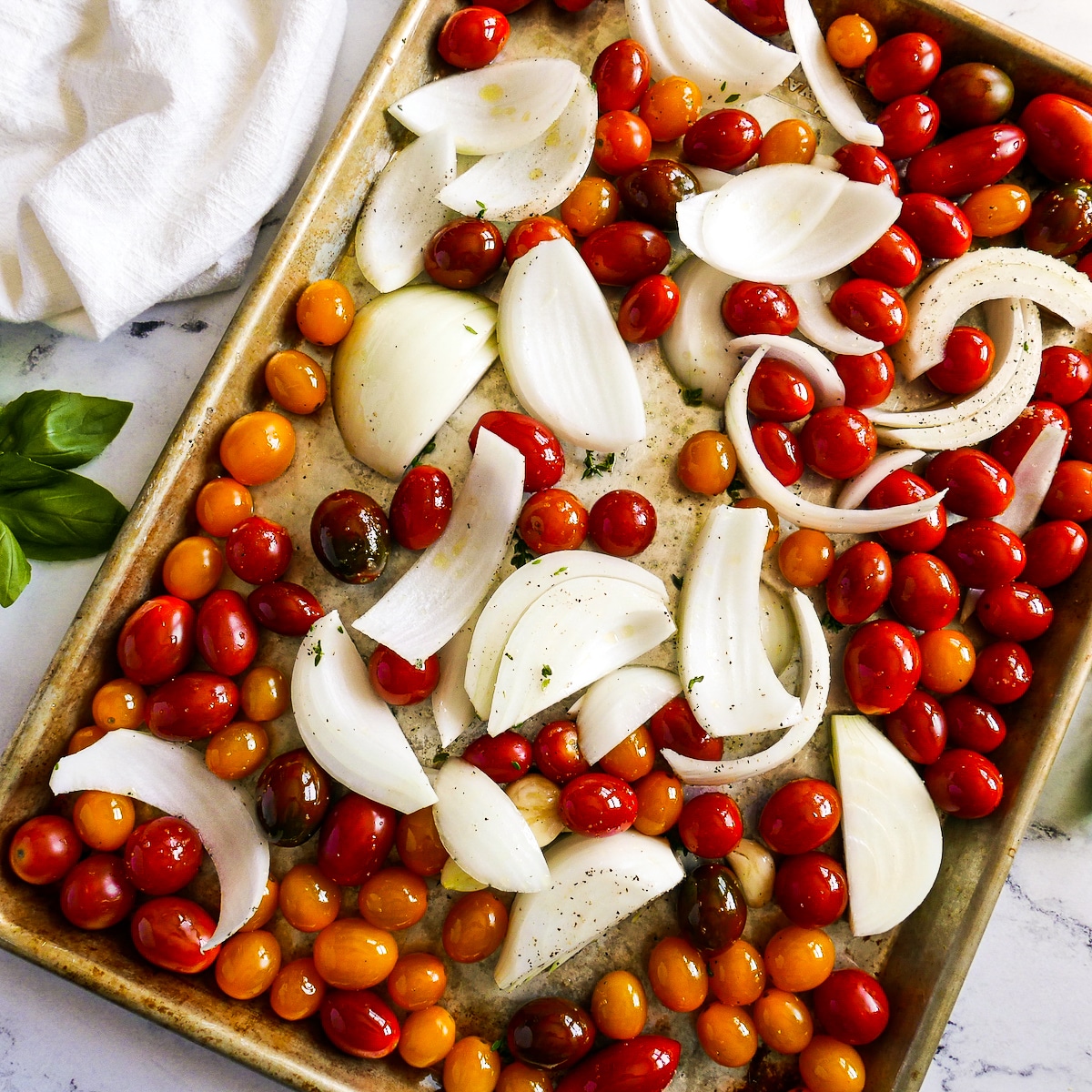 Sauce ingredients coated with olive oil and spread out on a baking sheet.