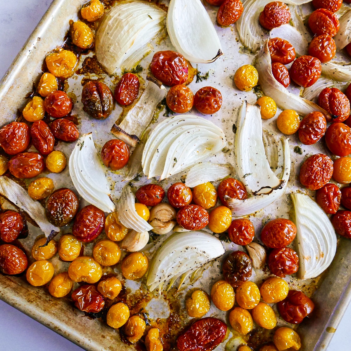 Caramelized tomatoes, onions, and garlic on a baking sheet.