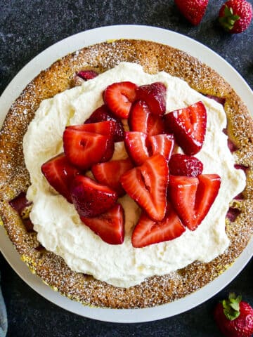 Strawberry buttermilk cake topped with whipped cream and strawberries.