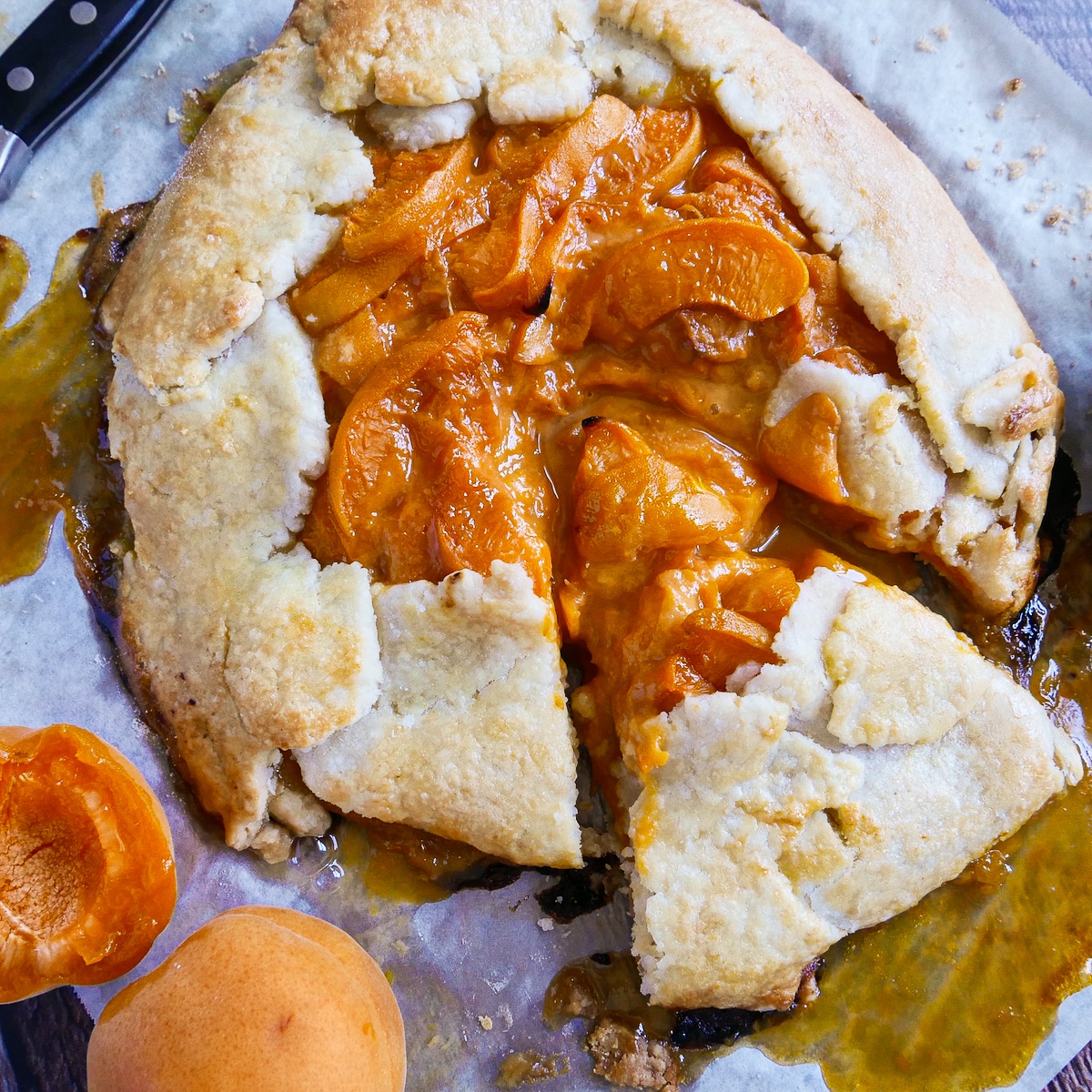 Sliced galette on parchment with a knife resting nearby.