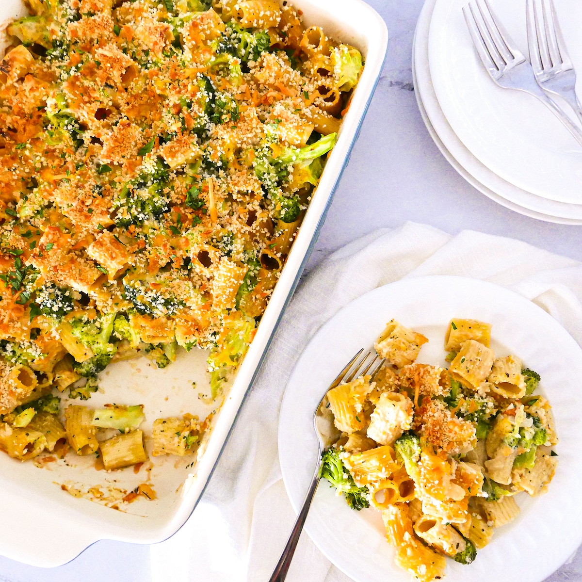 Baked pasta with broccoli on a white plate with fork and napkin.