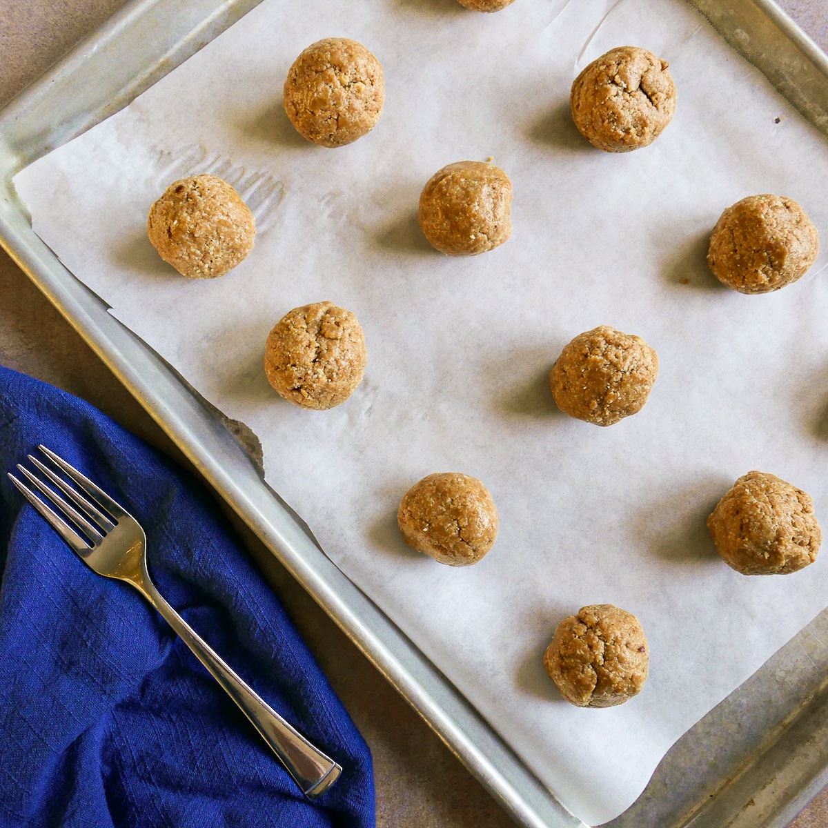 cookie dough rolled into balls on a baking sheet lined with parchment paper. 