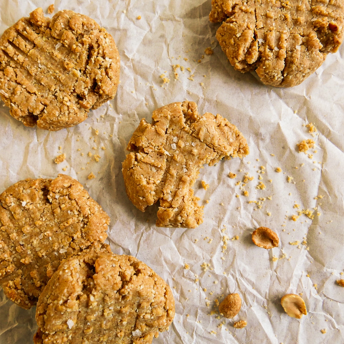 Half-eaten gluten free peanut butter cookies with crumbs.