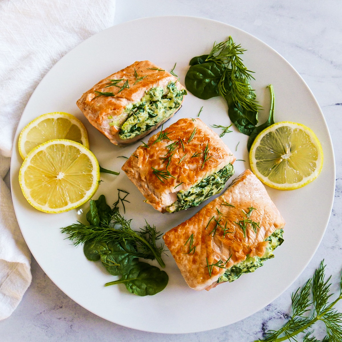 stuffed salmon with spinach arranged on a white platter.