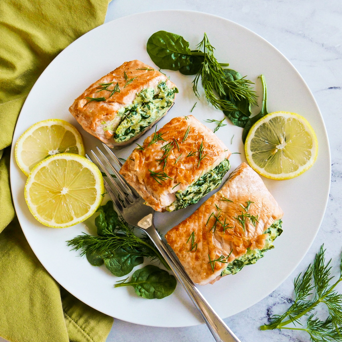 Plate of stuffed salmon with cream cheese, a fork, and lemon slices.