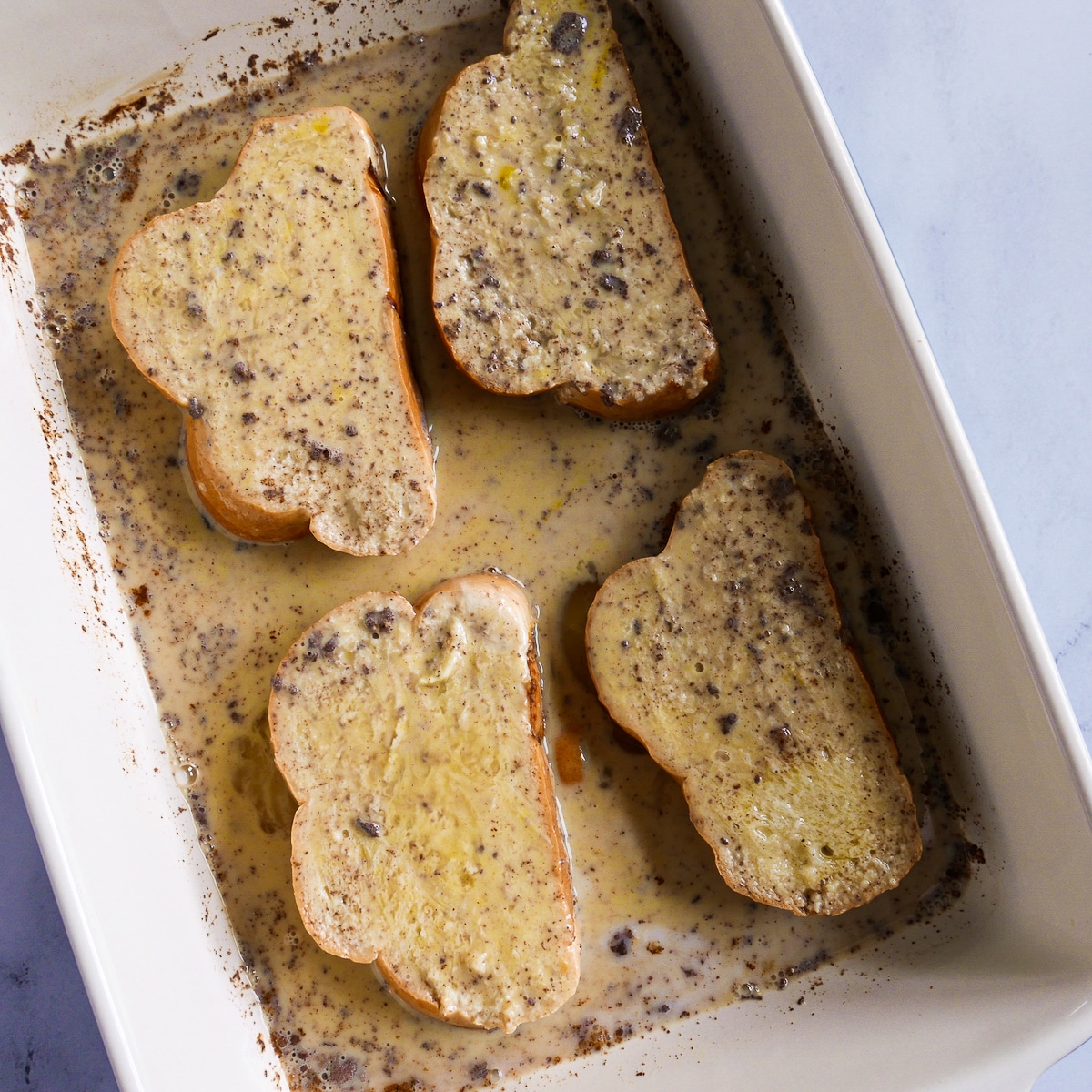 Challah bread flipped onto other side in baking dish.