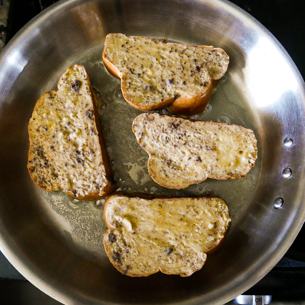 Challah placed in a large skillet with melted butter.