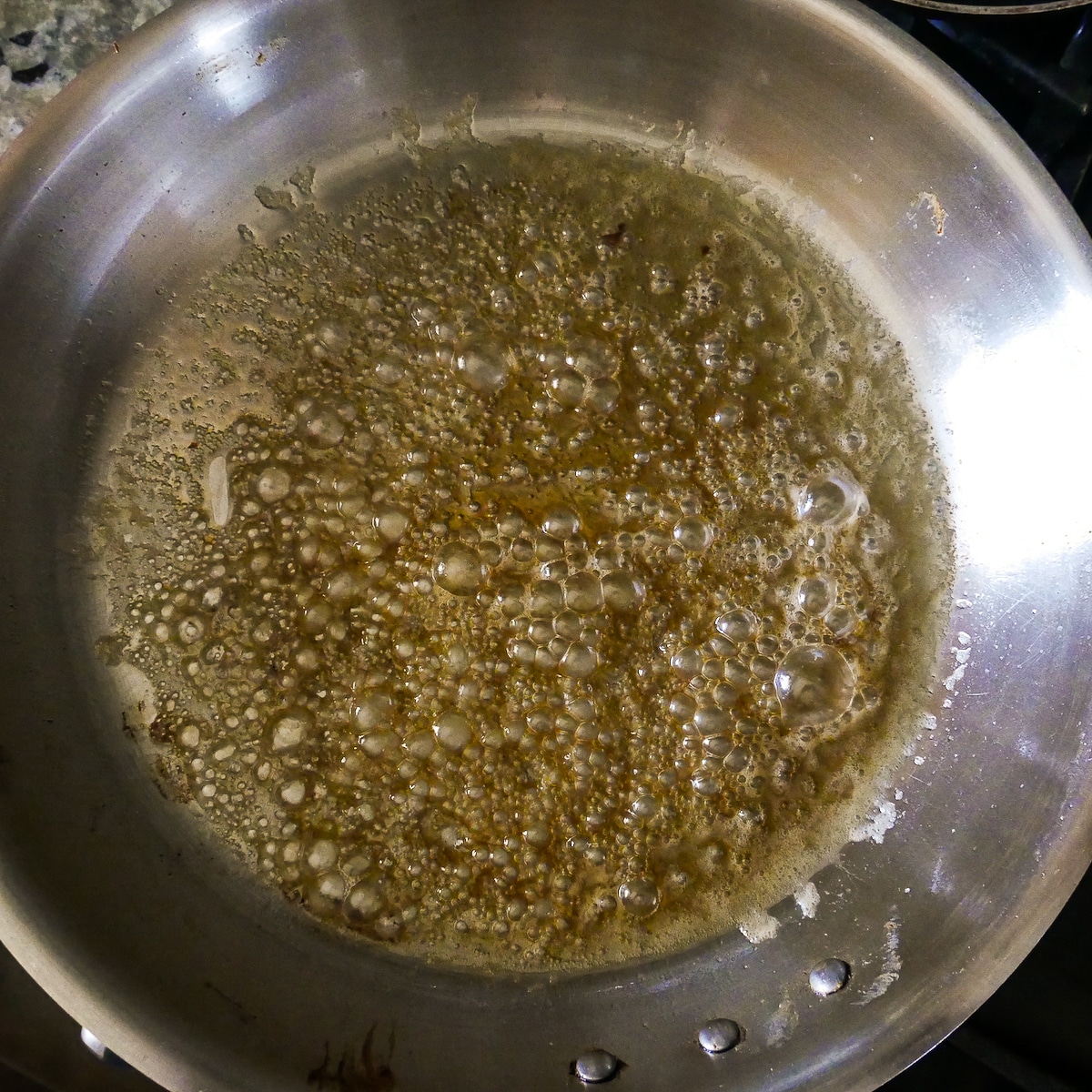 Sugar and water turning foamy in a large skillet.