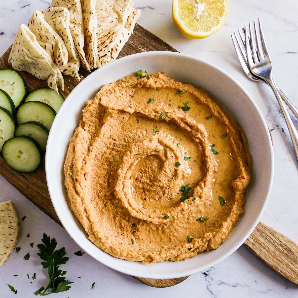 Bowl of spicy hummus garnished with fresh parsley.