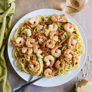 Large plate of garlic shrimp spaghetti with two forks.