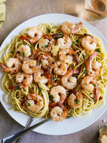 Large plate of garlic shrimp spaghetti with two forks.