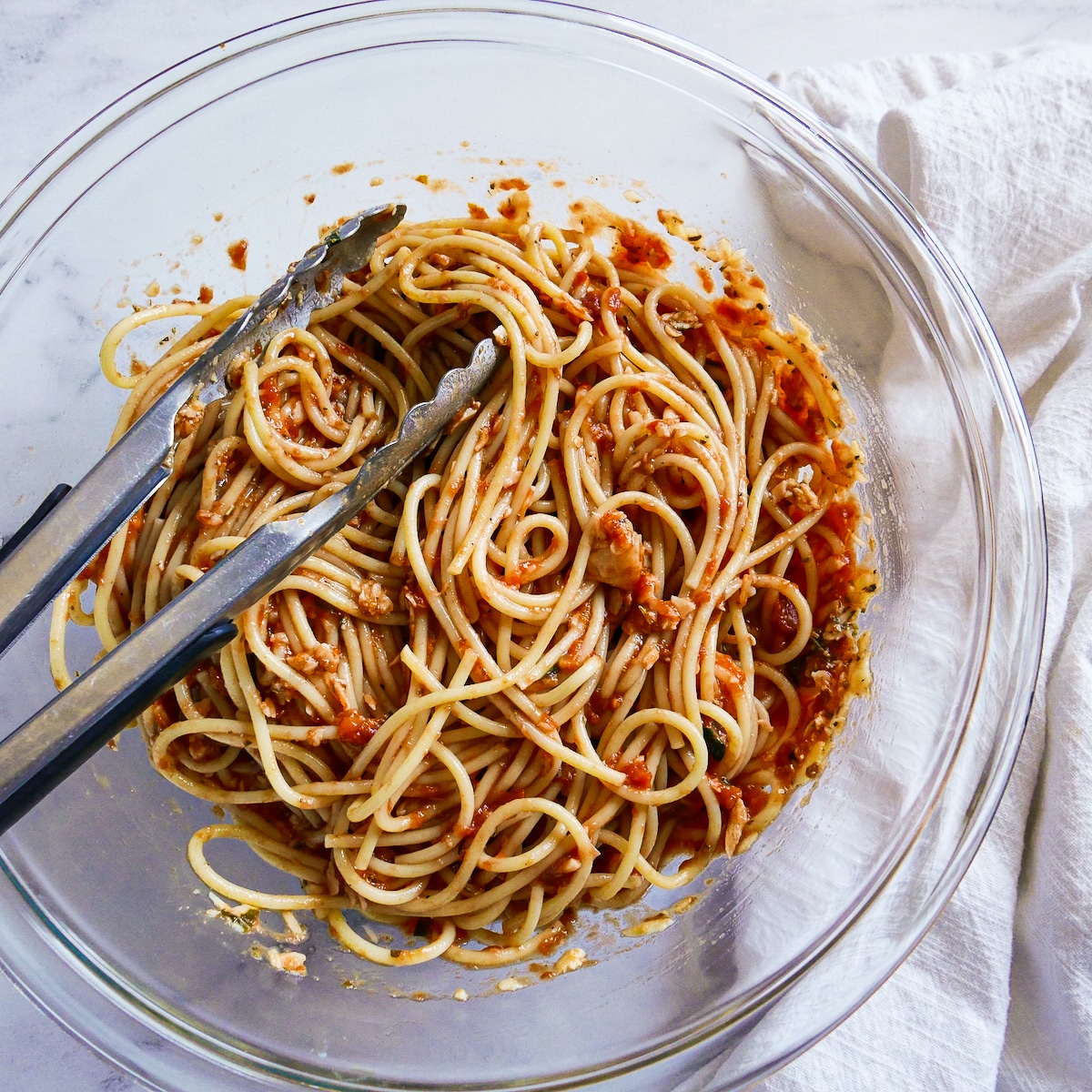 Leftover spaghetti tossed with other ingredients in a mixing bowl.