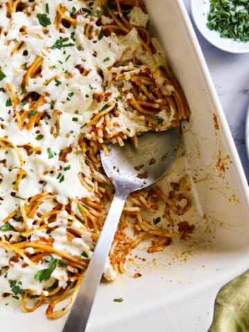 Baked leftover spaghetti in a baking dish with a large spoon.