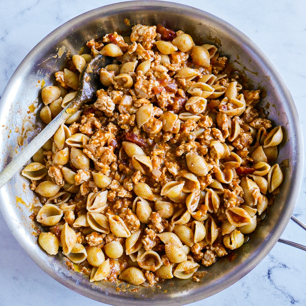 pasta-cheese-and-meat.jpg Cooked pasta and shredded cheese added to meat mixture in pan.