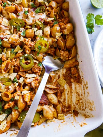 Taco pasta bake in a baking dish with a large spoon.