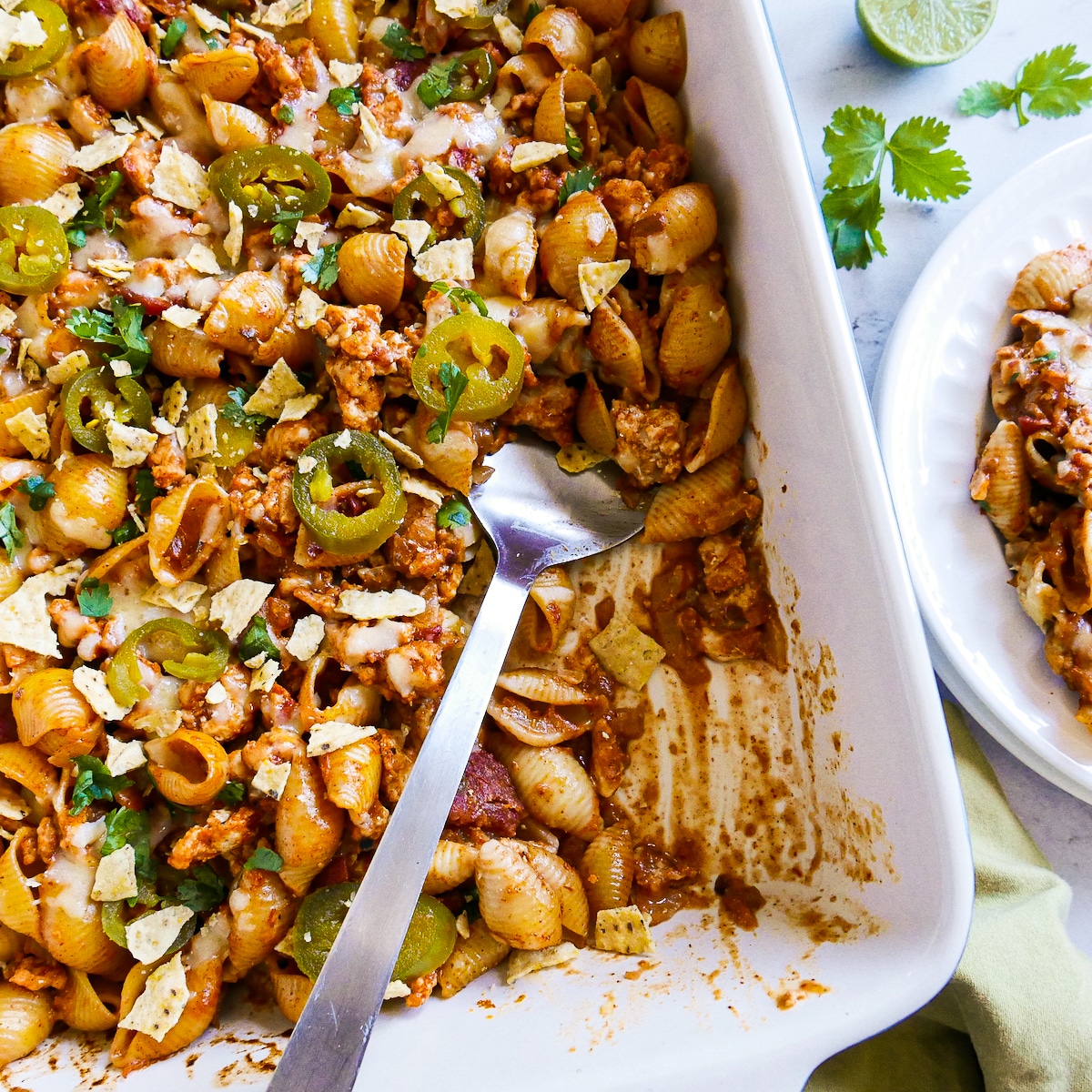 Taco pasta bake in a baking dish with a large spoon.