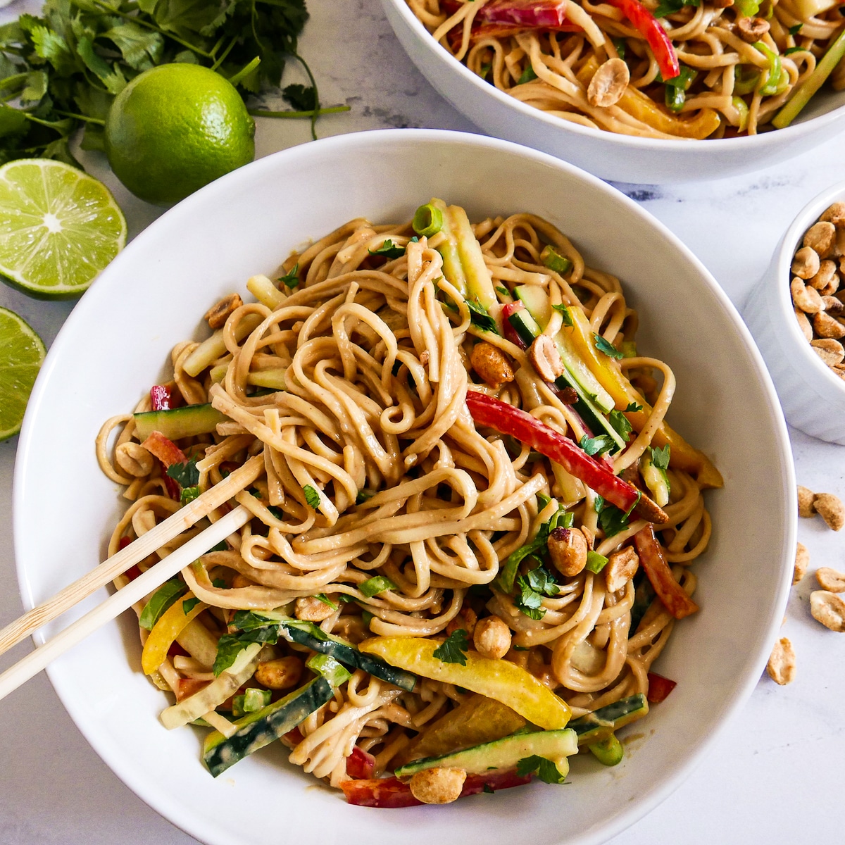 white bowl with Thai peanut noodles and a pair of chopsticks.