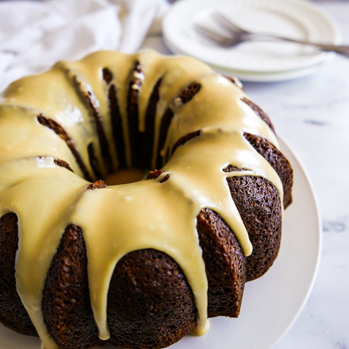 spice bundt cake on a white platter with forks and plates in the background.