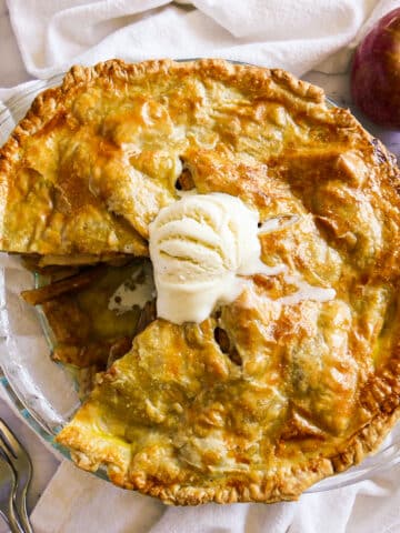 Sliced apple pie with melting ice cream on top.