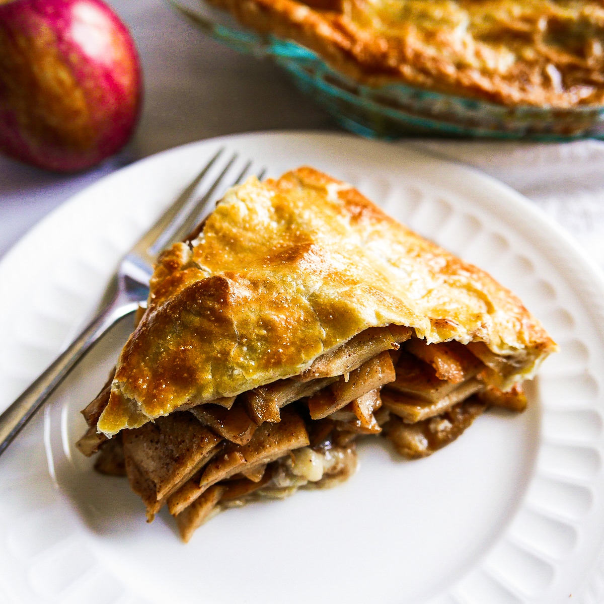 slice of apple pie with fork on a white plate. 