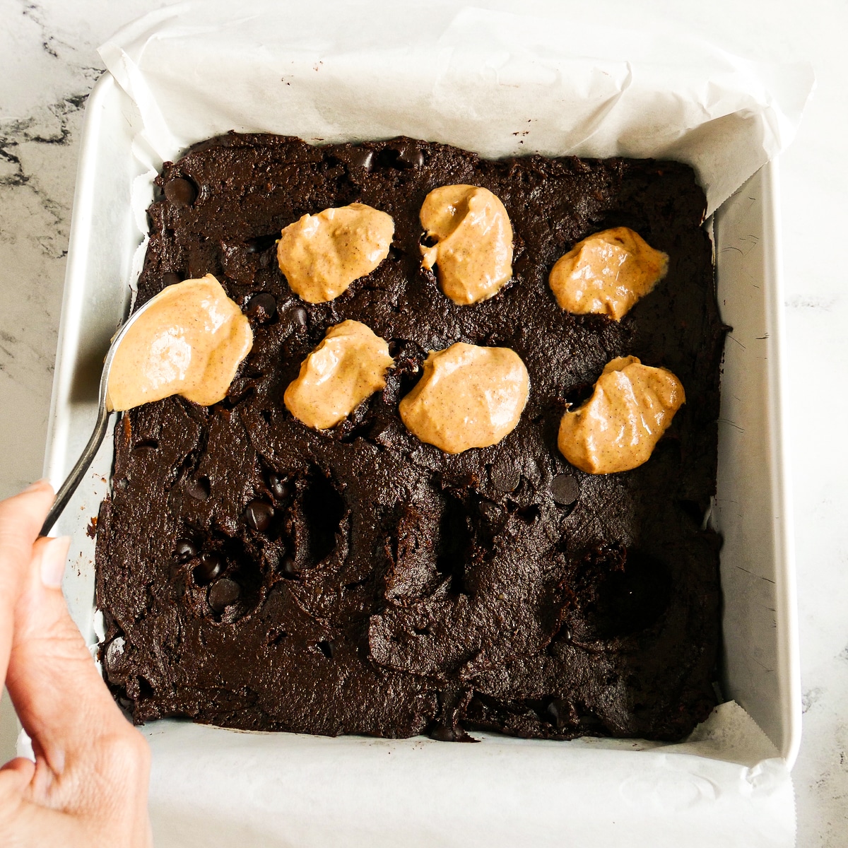 Dropping spoonfuls of pumpkin swirl onto brownie batter.