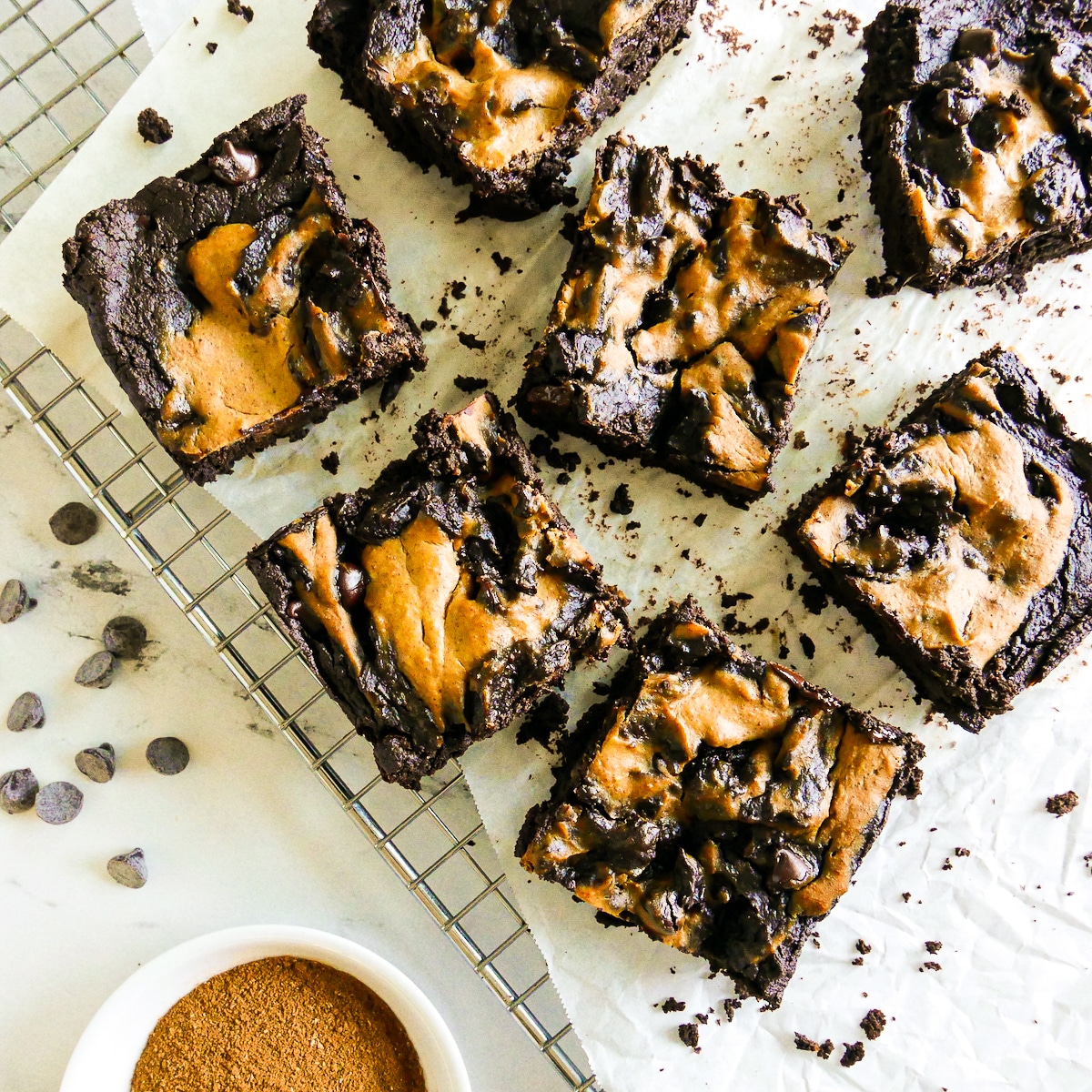 Sliced pumpkin brownies on a cooling rack with crumbs.