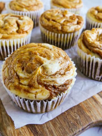 Baked pumpkin cream cheese muffins arranged on a cutting board.