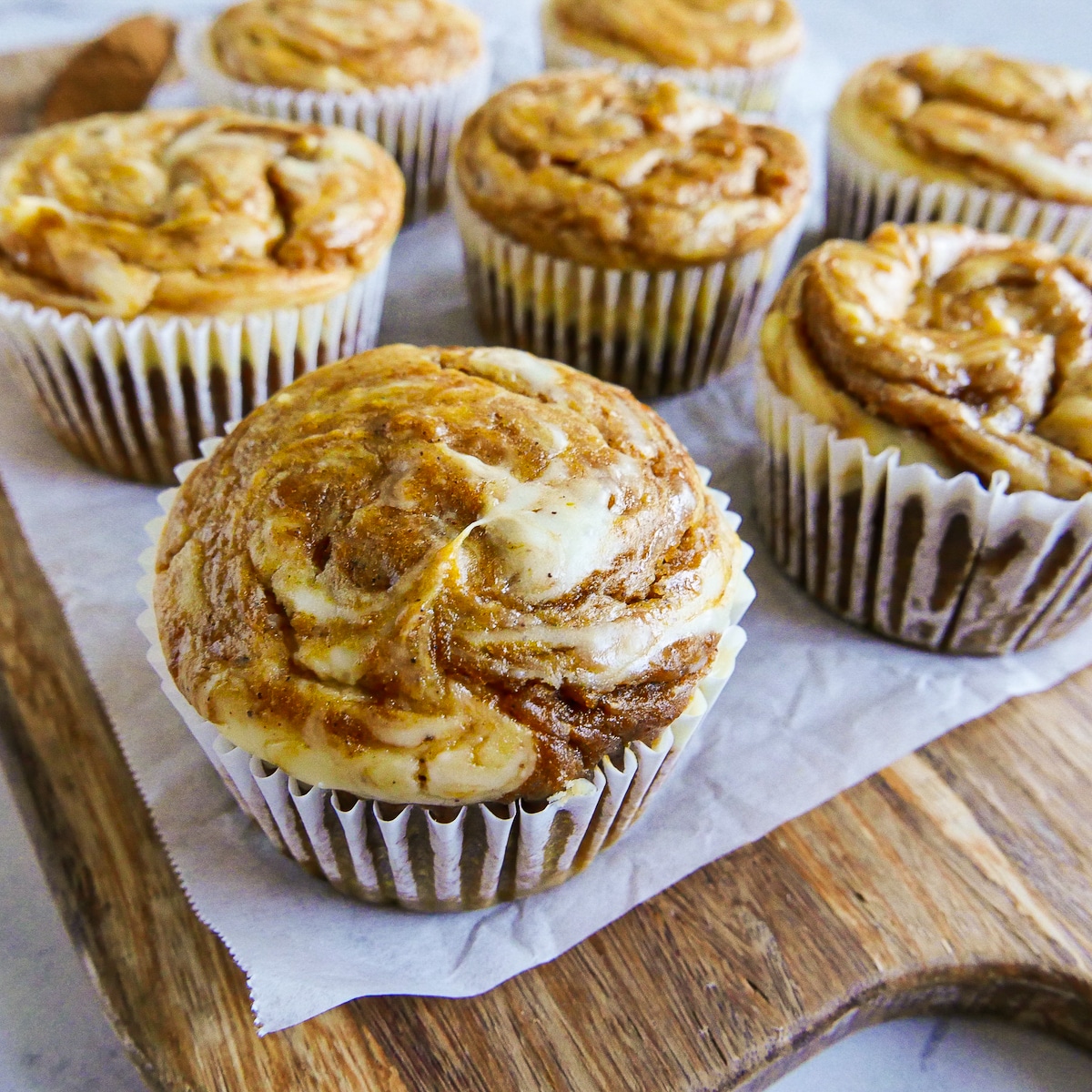 Baked pumpkin cream cheese muffins arranged on a cutting board.