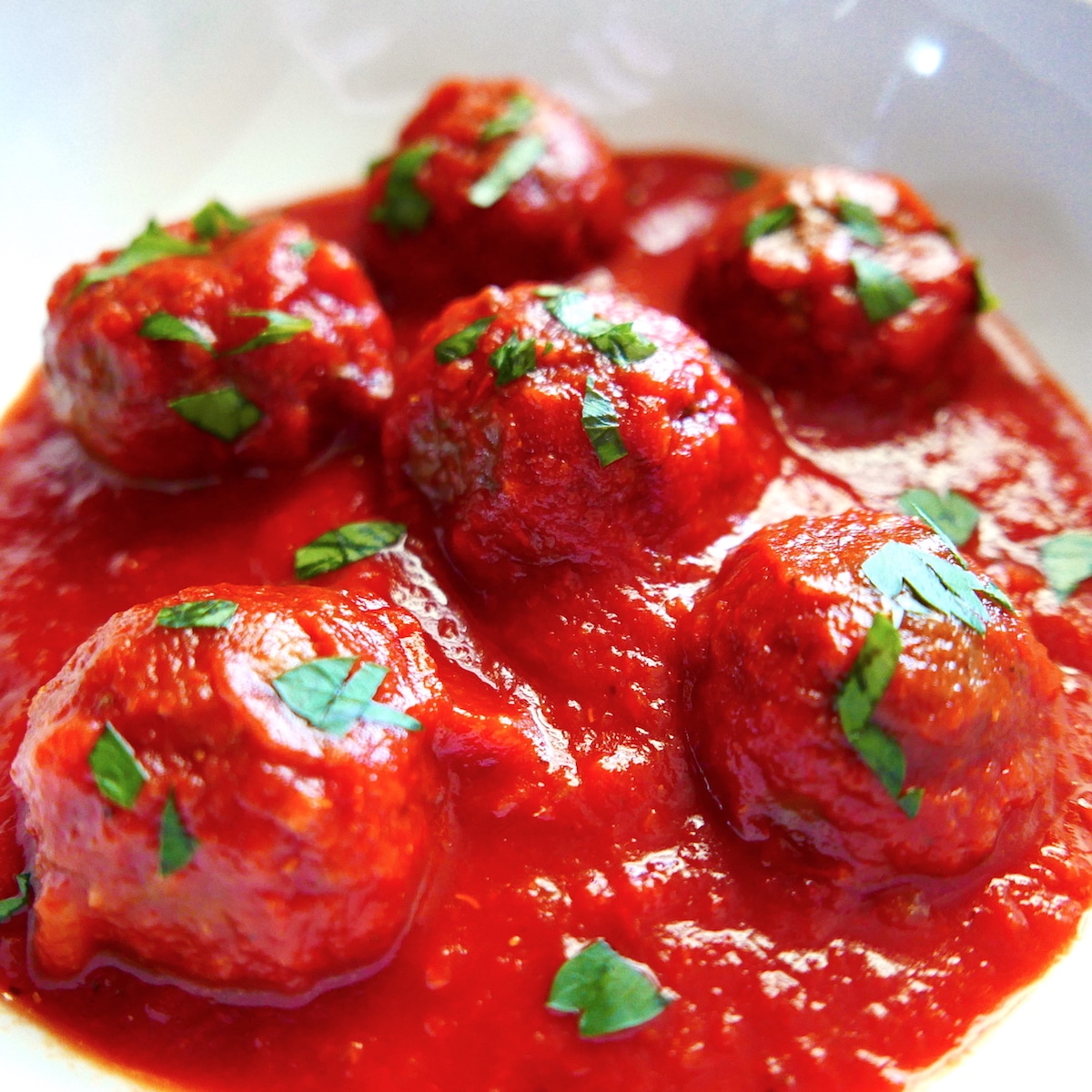 Impossible meatballs resting in a bowl of pasta sauce.