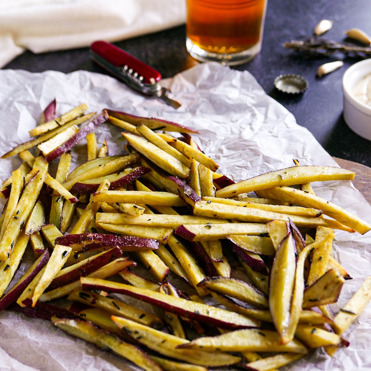 Sweet potato fries with garlic and rosemary and a beer bottle opener in background.