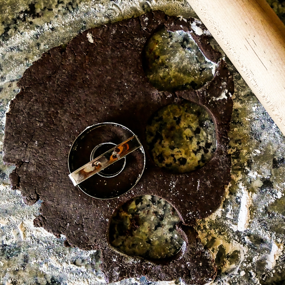 Cutting out donuts on a floured surface with a donut cutter. 