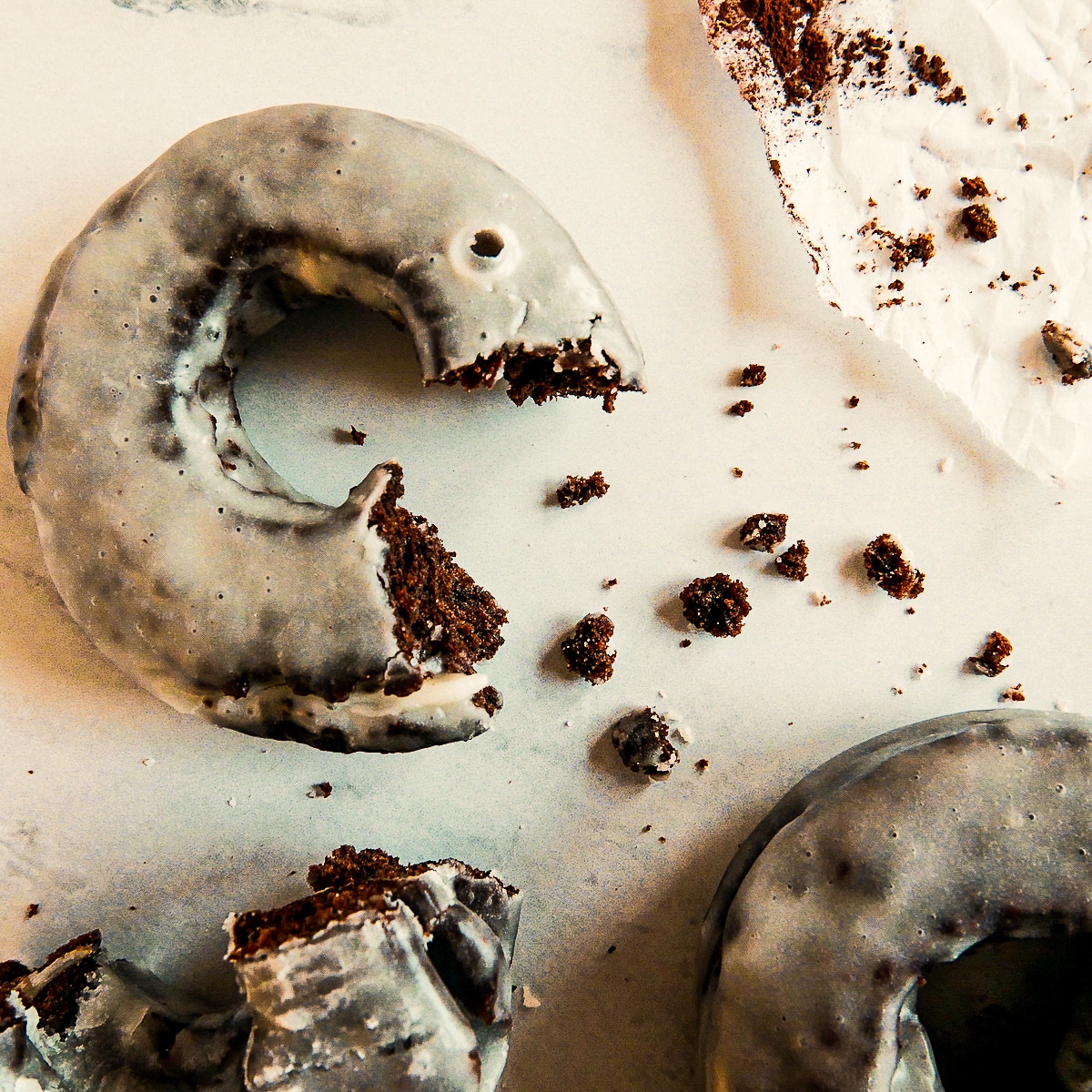 Old fashioned donut on a table with bite taken out of it.