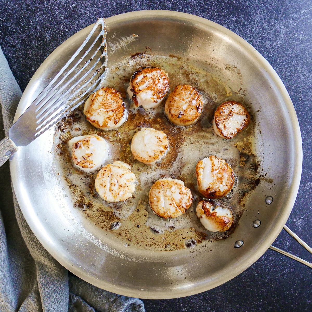 Seared scallops with a golden brown crust in a large skillet.