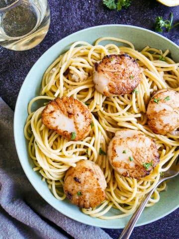 Bowl of creamy scallop linguine with seared scallops and fresh parsley.