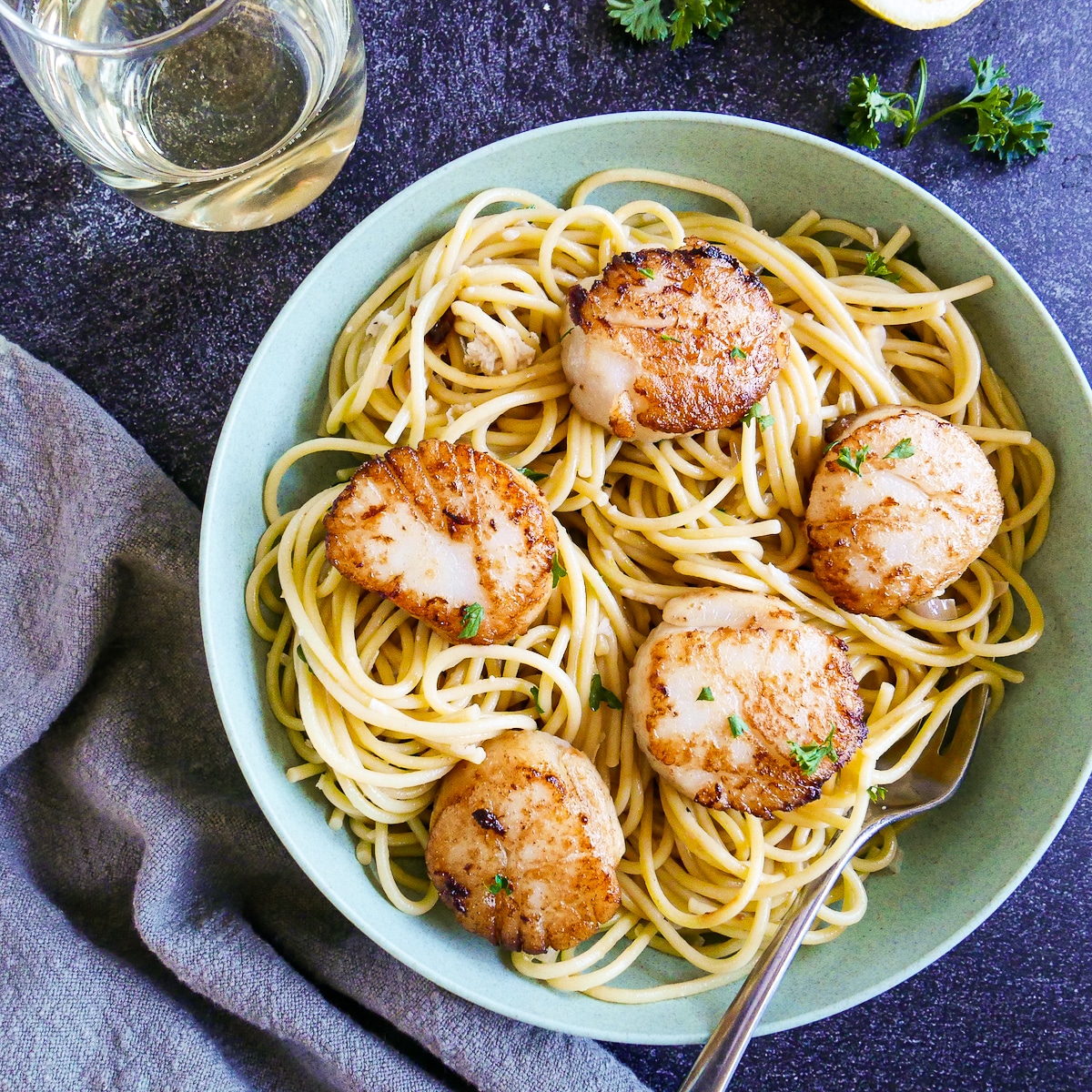 Bowl of creamy scallop linguine with seared scallops and fresh parsley.