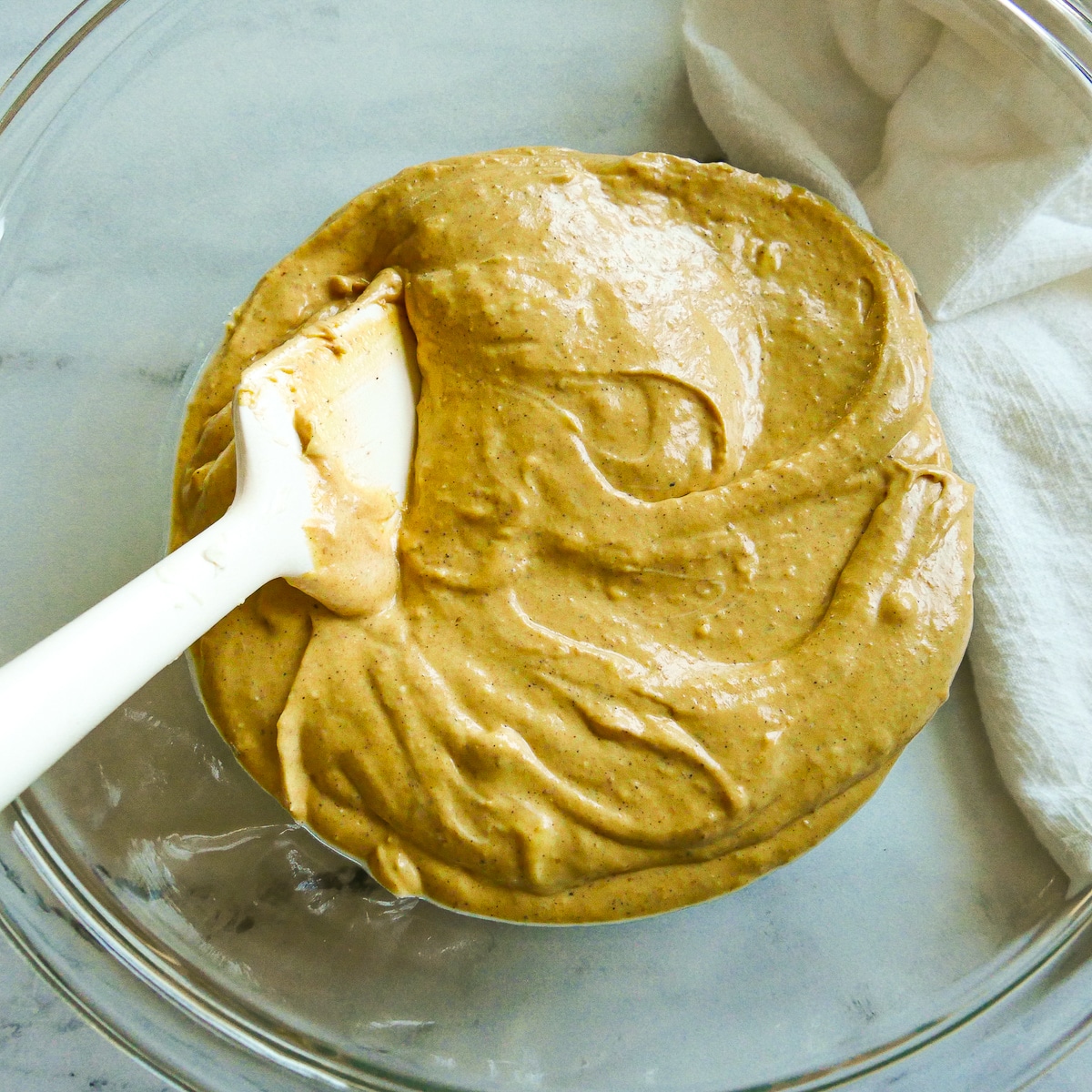 Canned pumpkin and pumpkin spice added to cream cheese mixture in a mixing bowl.