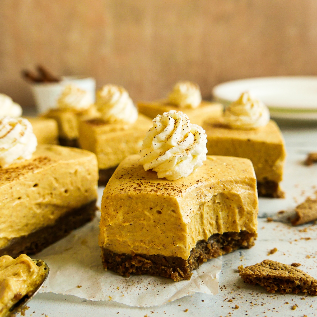 Silky no bake cheesecake bars with gingersnap crust arranged on a table.