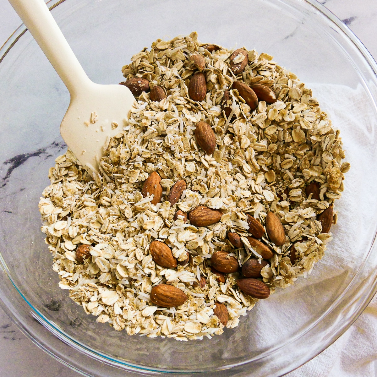 Mixing the oats, almonds, coconut, and brown sugar in a large bowl.
