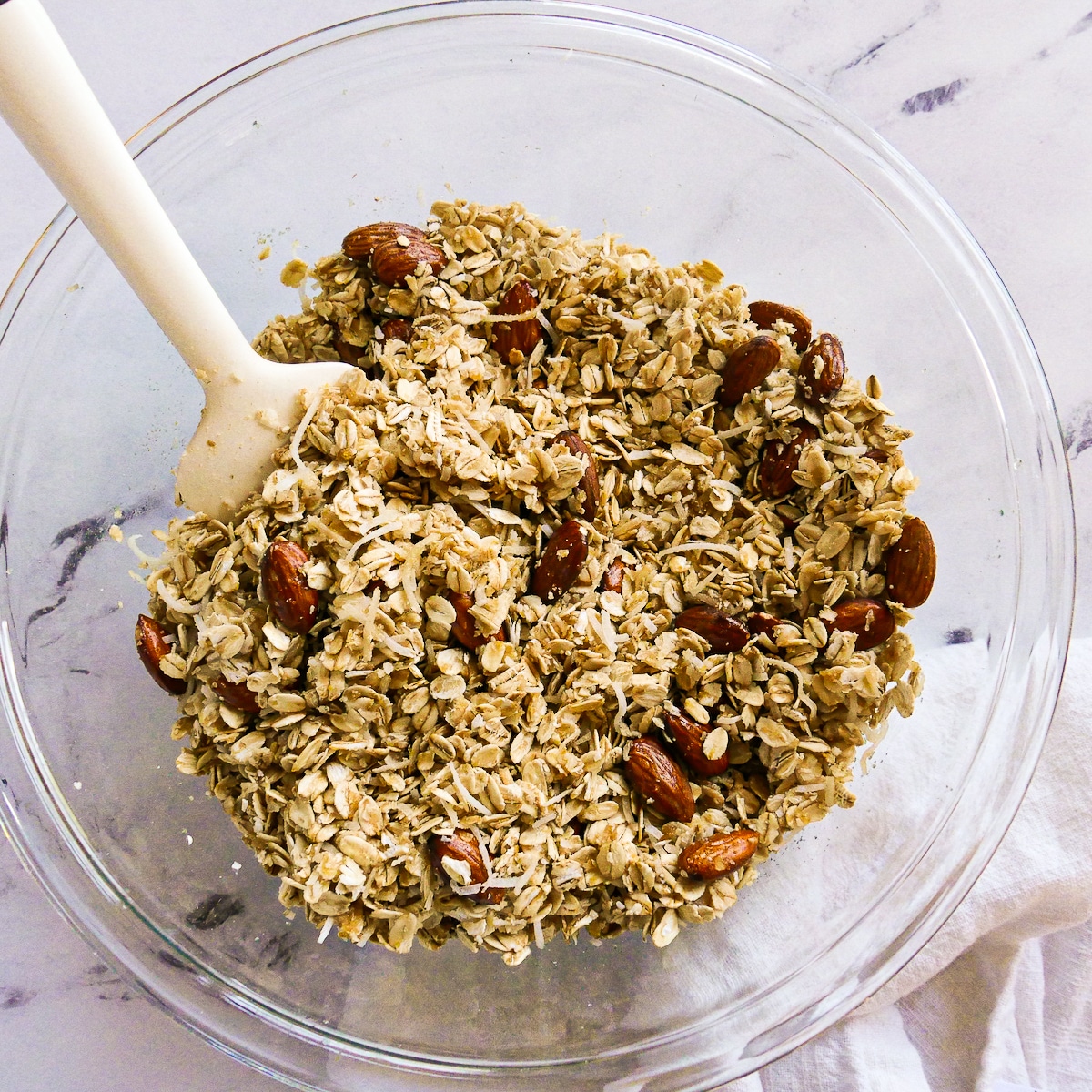 Oil and maple syrup mixture added to dry oats mixture in a bowl.