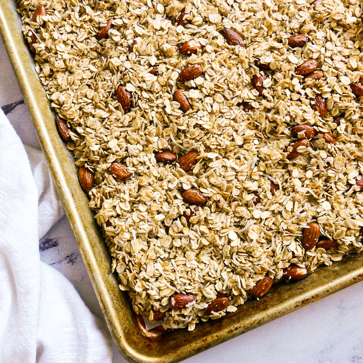 Granola mixture spread out onto a parchment lined baking sheet.