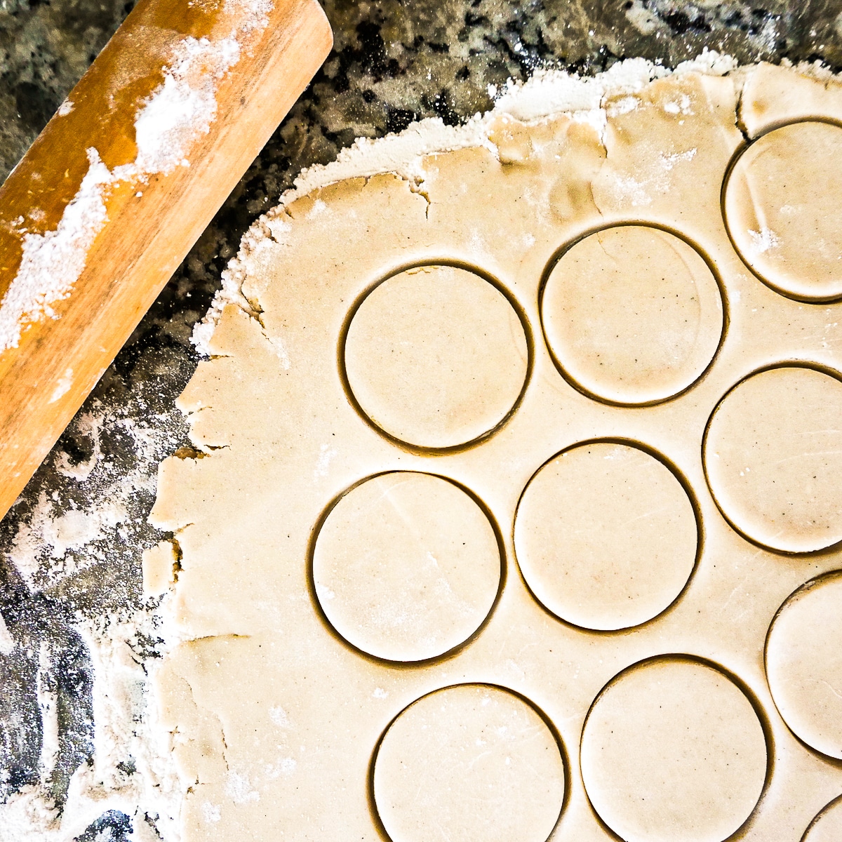 Cookie dough being cut with a cookie cutter.