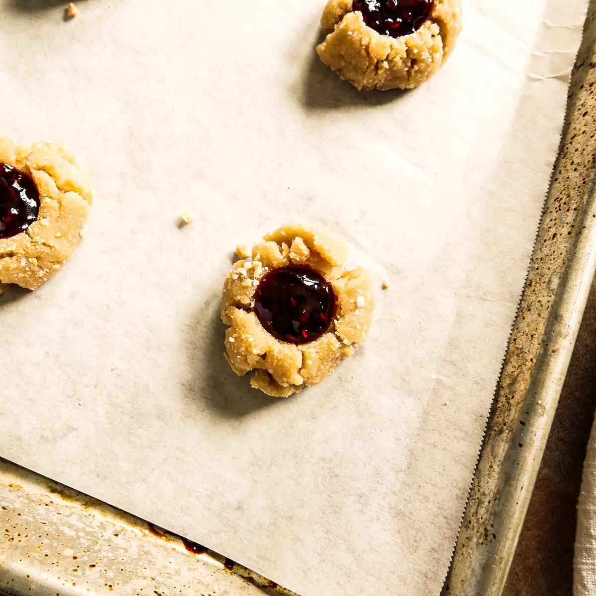 cookie dough filled with raspberry jam on a baking sheet.