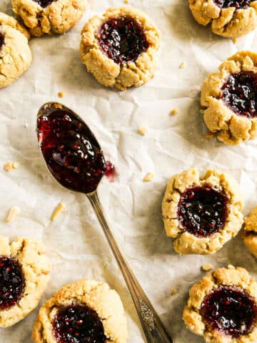 chewy thumbprint cookies with almond flour arranged on parchment paper.